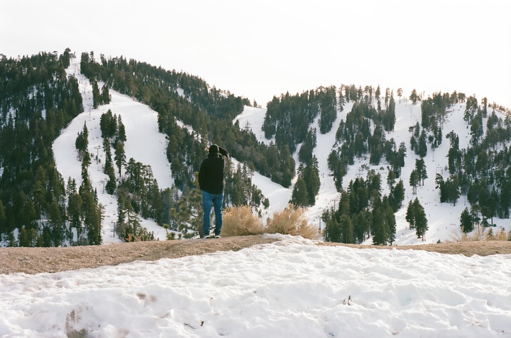 a man standing on top of a snow covered slope