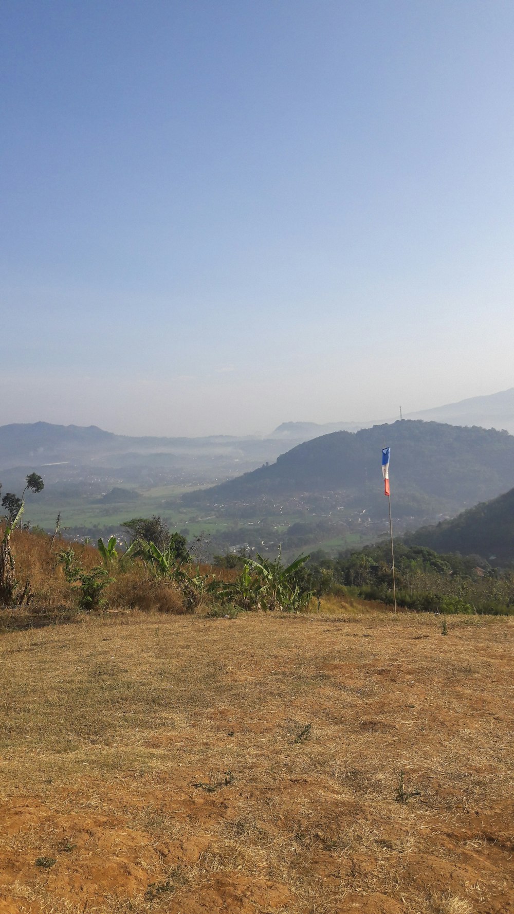 a field with a flag and mountains in the background