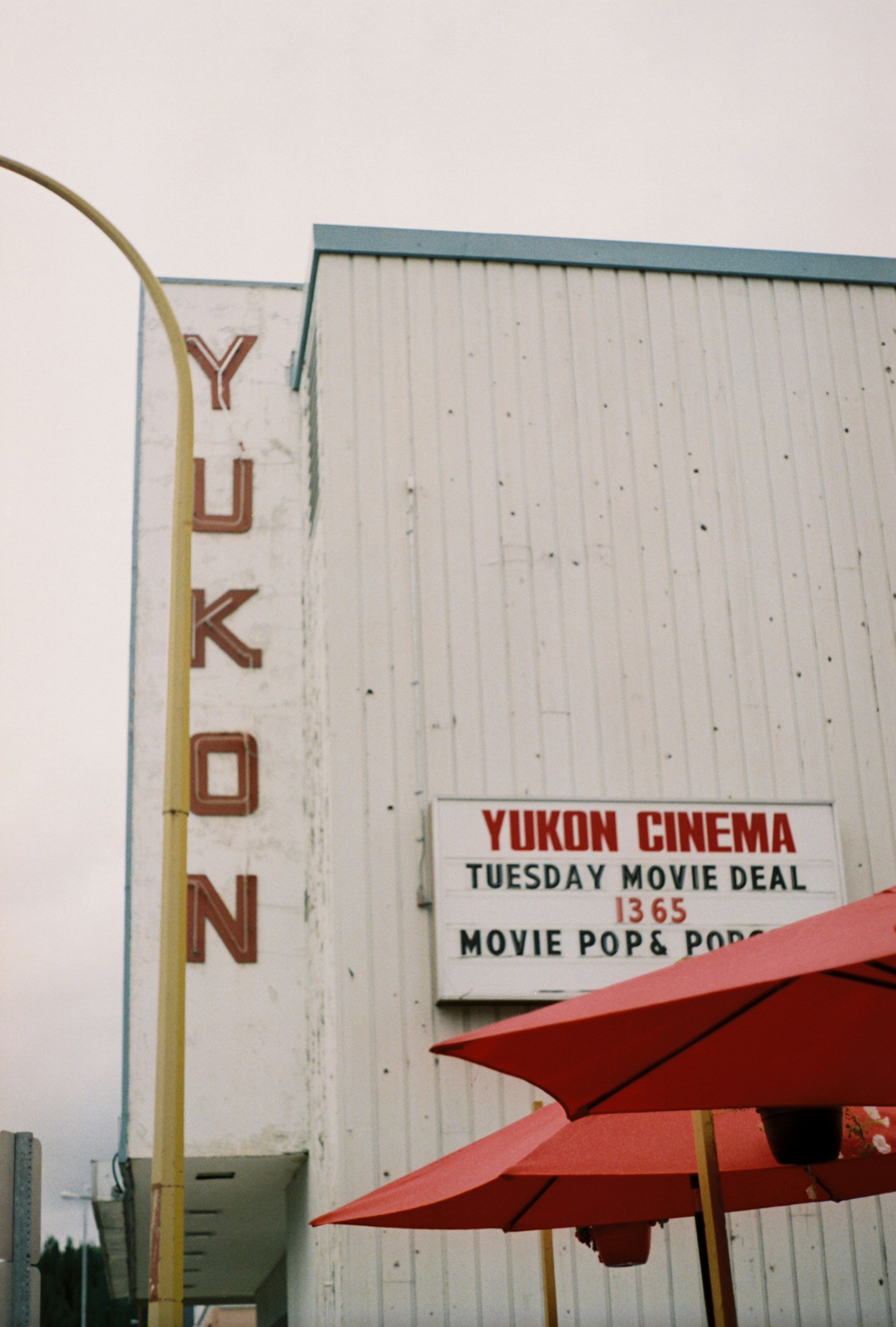 a movie theater with red umbrellas in front of it