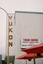 a movie theater with red umbrellas in front of it