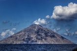 a large mountain with a very tall peak in the middle of the ocean