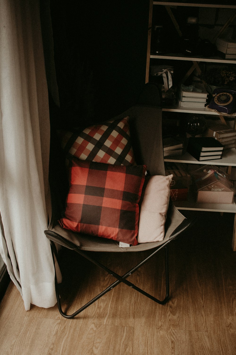 a chair with a pillow on top of it next to a book shelf