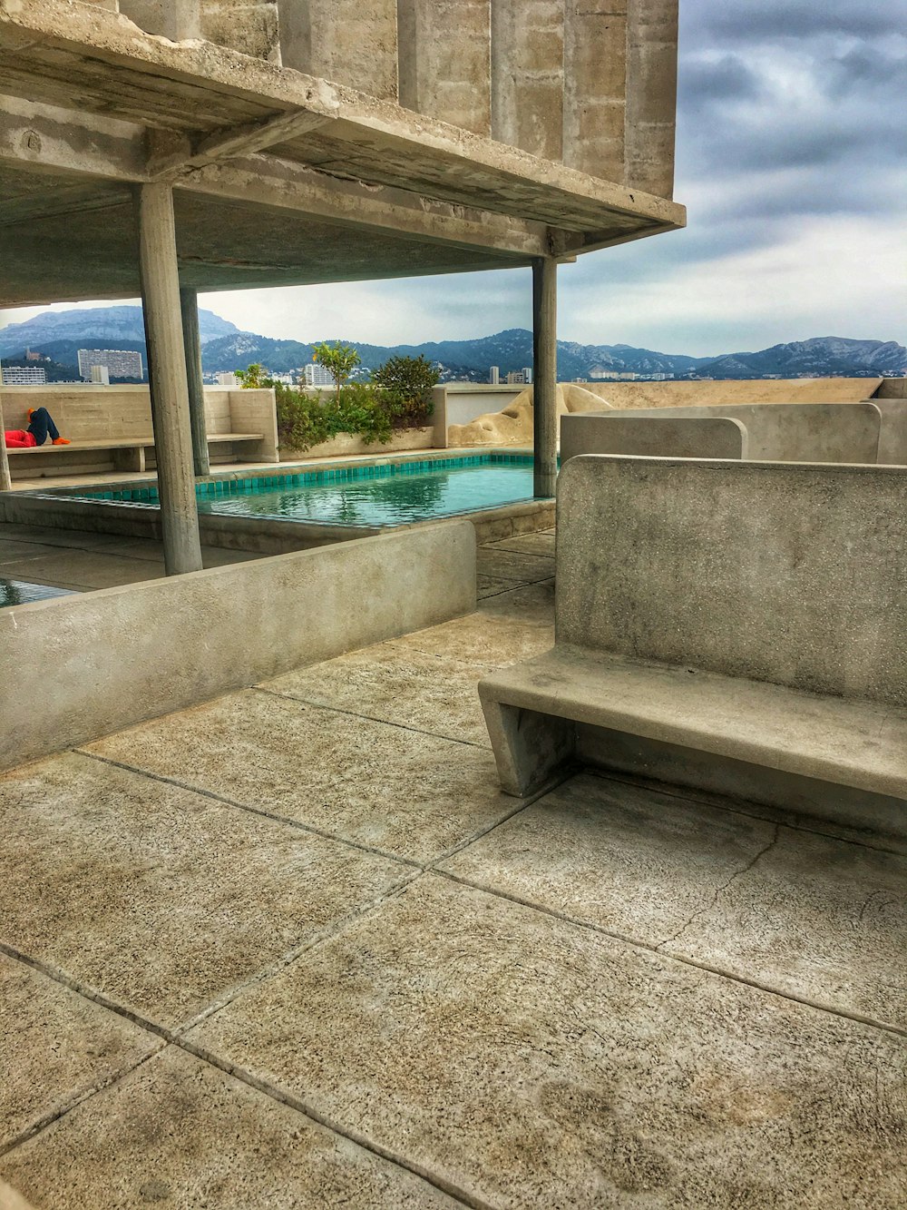 a concrete bench sitting next to a swimming pool