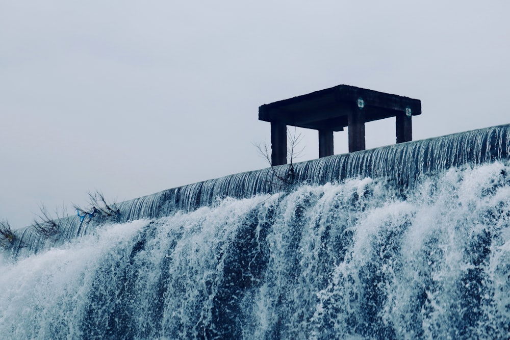 a large waterfall with a small structure on top of it