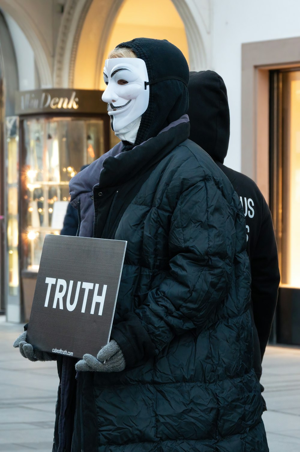 a man in a mask holding a sign that says truth