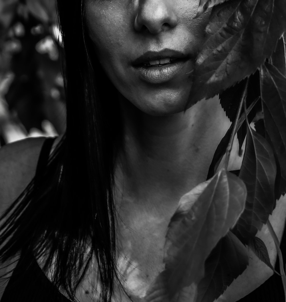 a black and white photo of a woman with leaves around her face