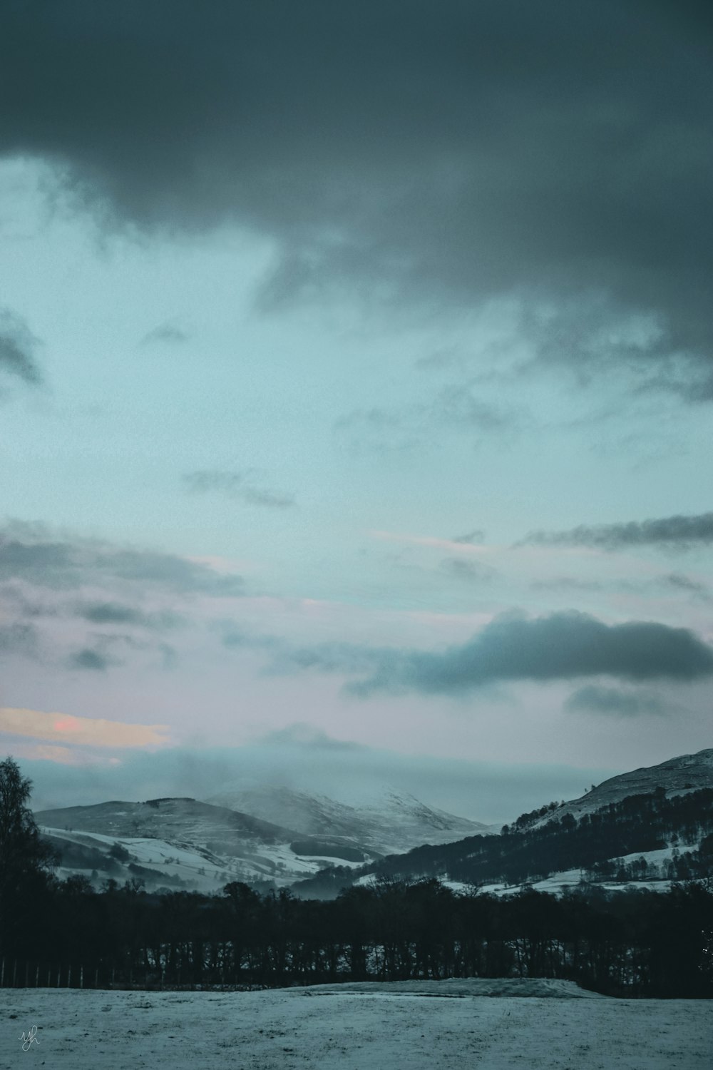 Un campo cubierto de nieve con montañas al fondo