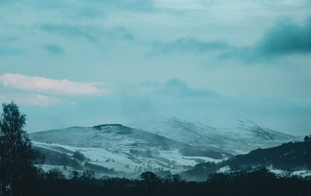 a mountain covered in snow under a cloudy sky