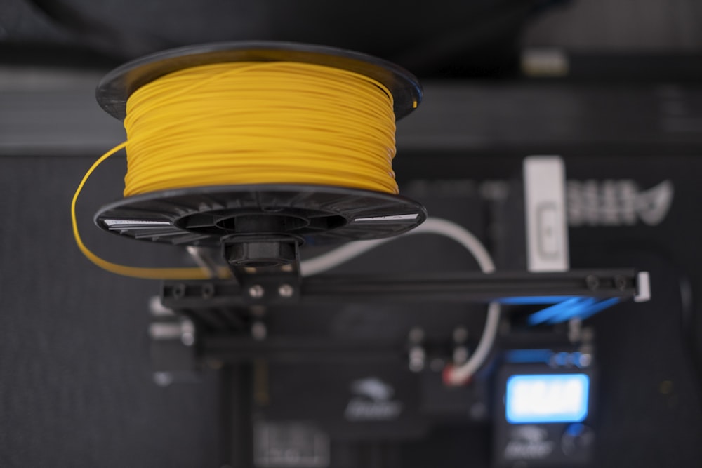 a spool of yellow wire sitting on top of a machine