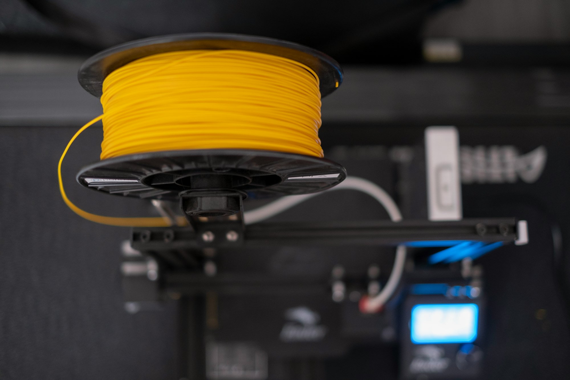 a spool of yellow filament wire sitting on top of a 3D printer