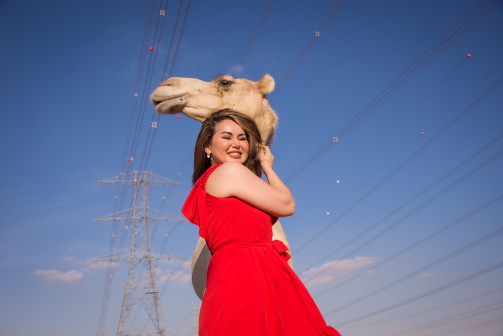 a woman in a red dress poses with a giraffe
