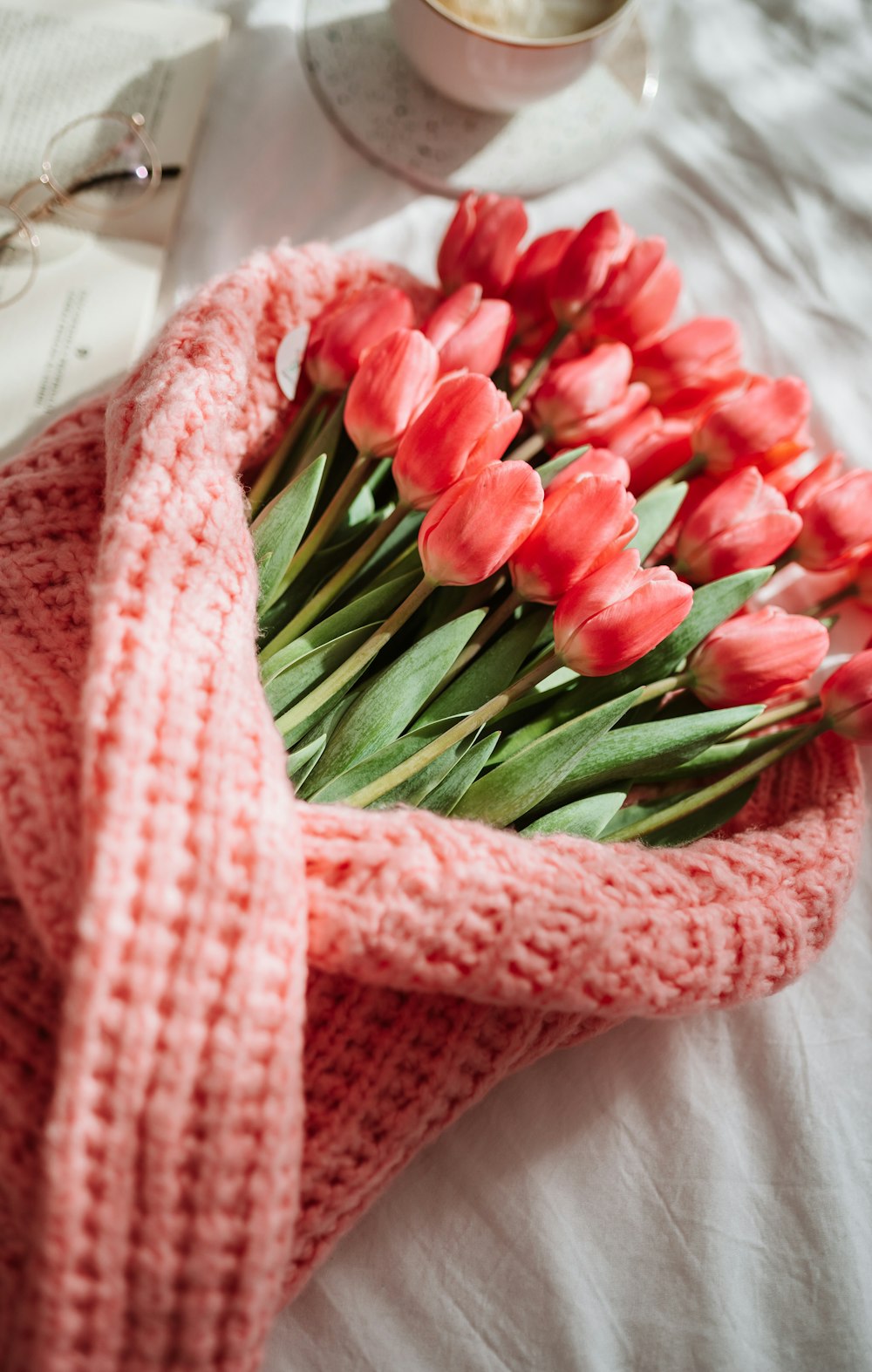 a bouquet of red tulips wrapped in a pink blanket