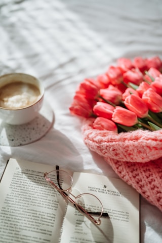 a cup of coffee and a book on a bed