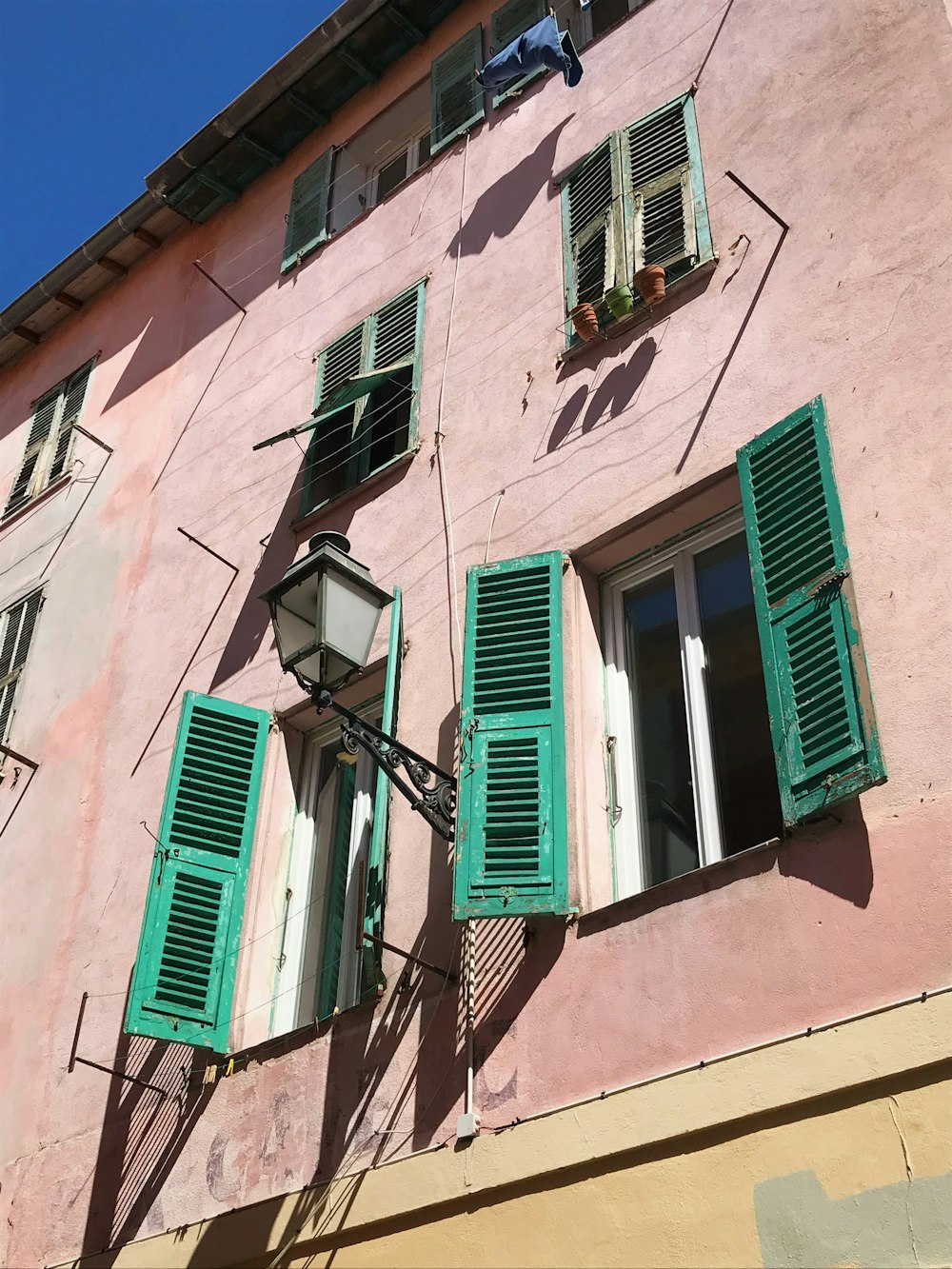 a pink building with green shutters and windows