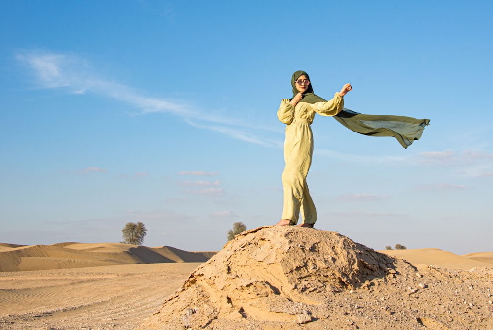 a woman in a yellow dress standing on top of a rock