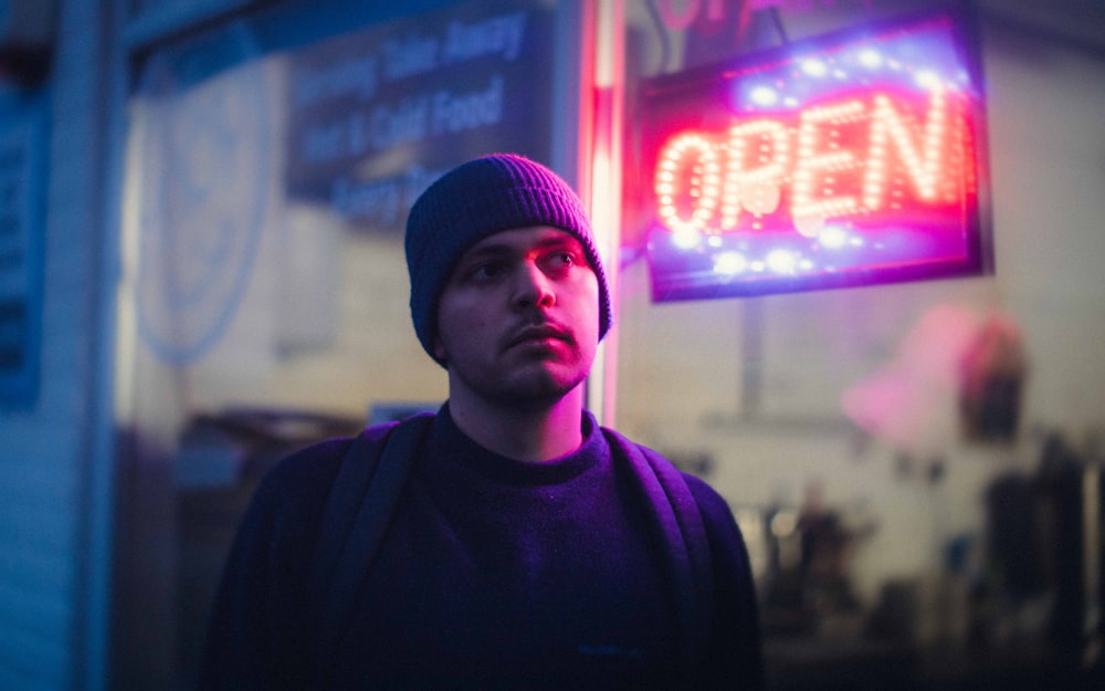 a man standing in front of a neon open sign