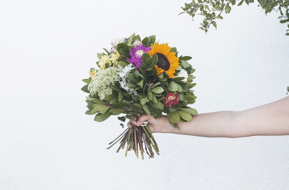 a person holding a bouquet of flowers in their hand