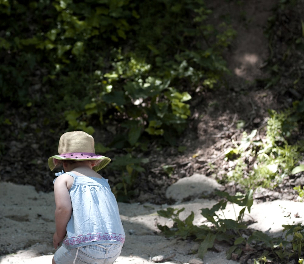 a little girl wearing a hat walking down a path