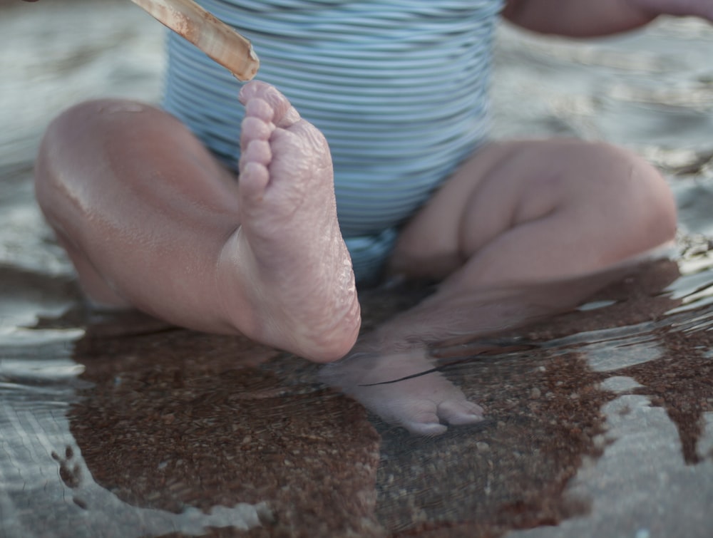 a person sitting in a body of water with their feet in the water