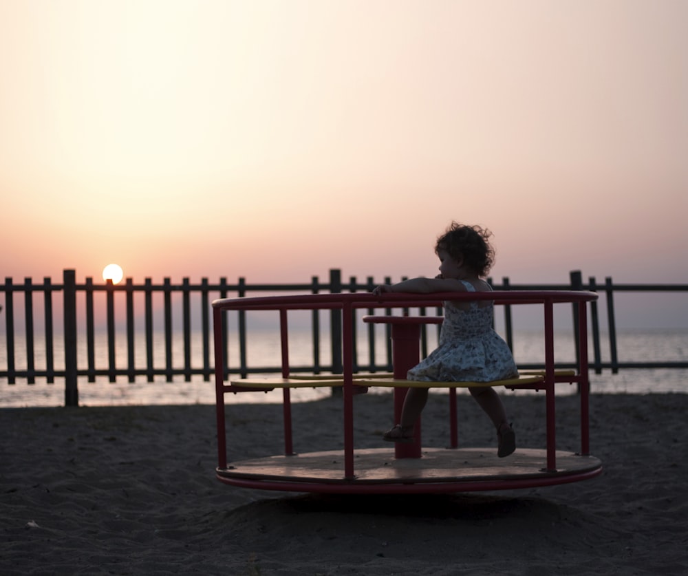 a little girl sitting on top of a red swing