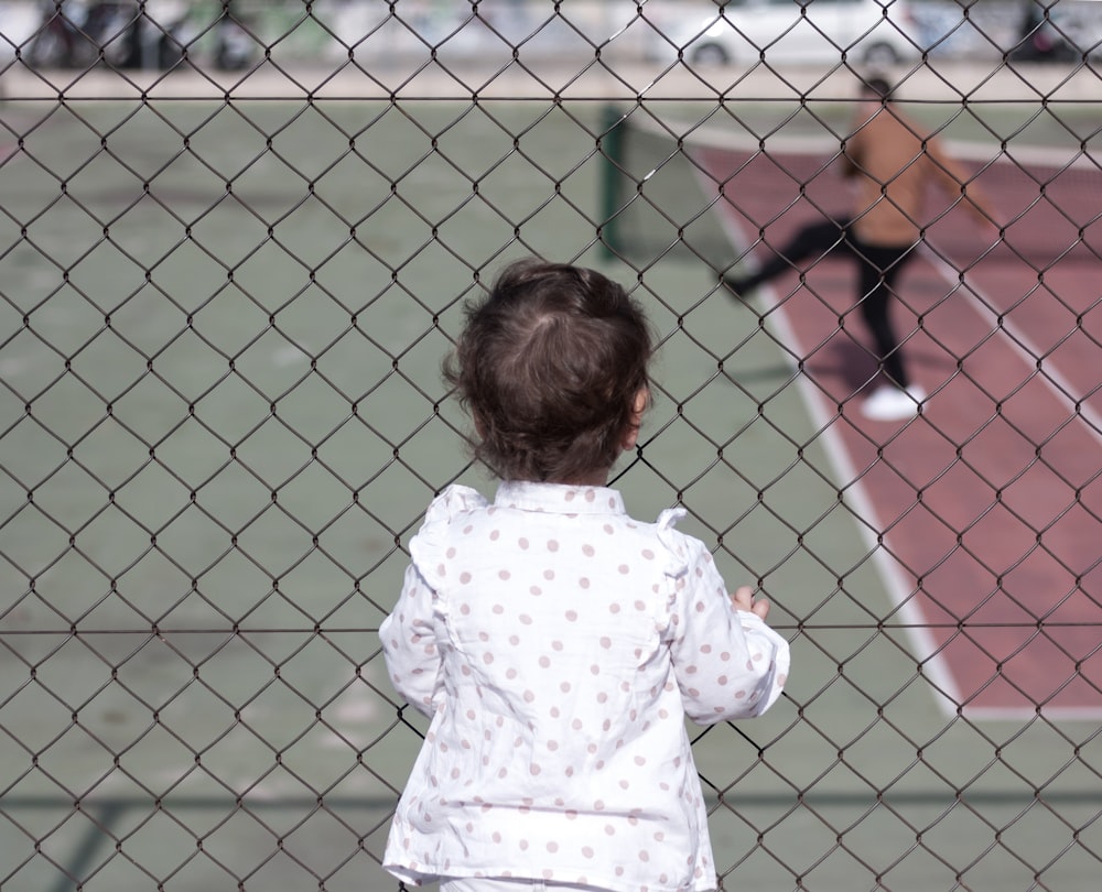 a little girl standing on a tennis court holding a racquet