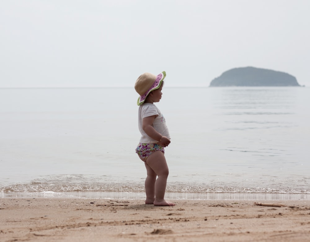 a little girl standing on top of a sandy beach