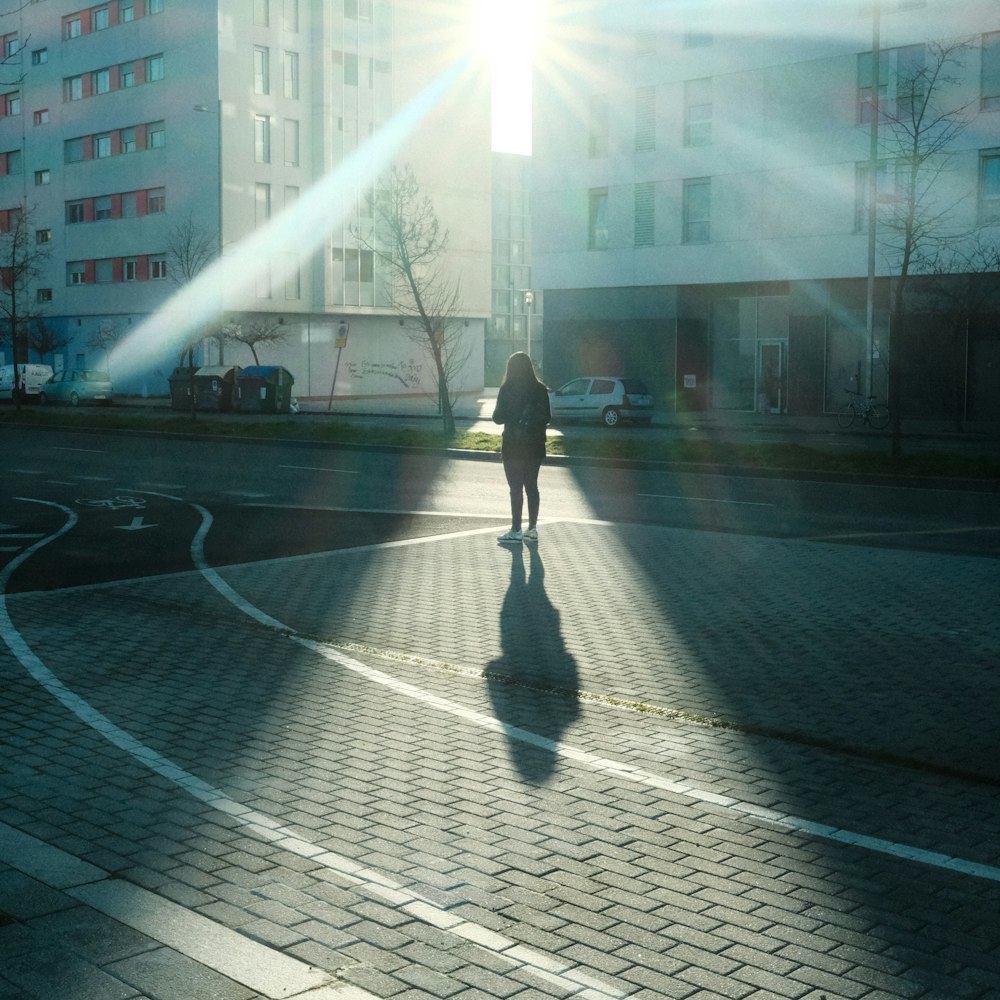 a person walking down a street in the sun