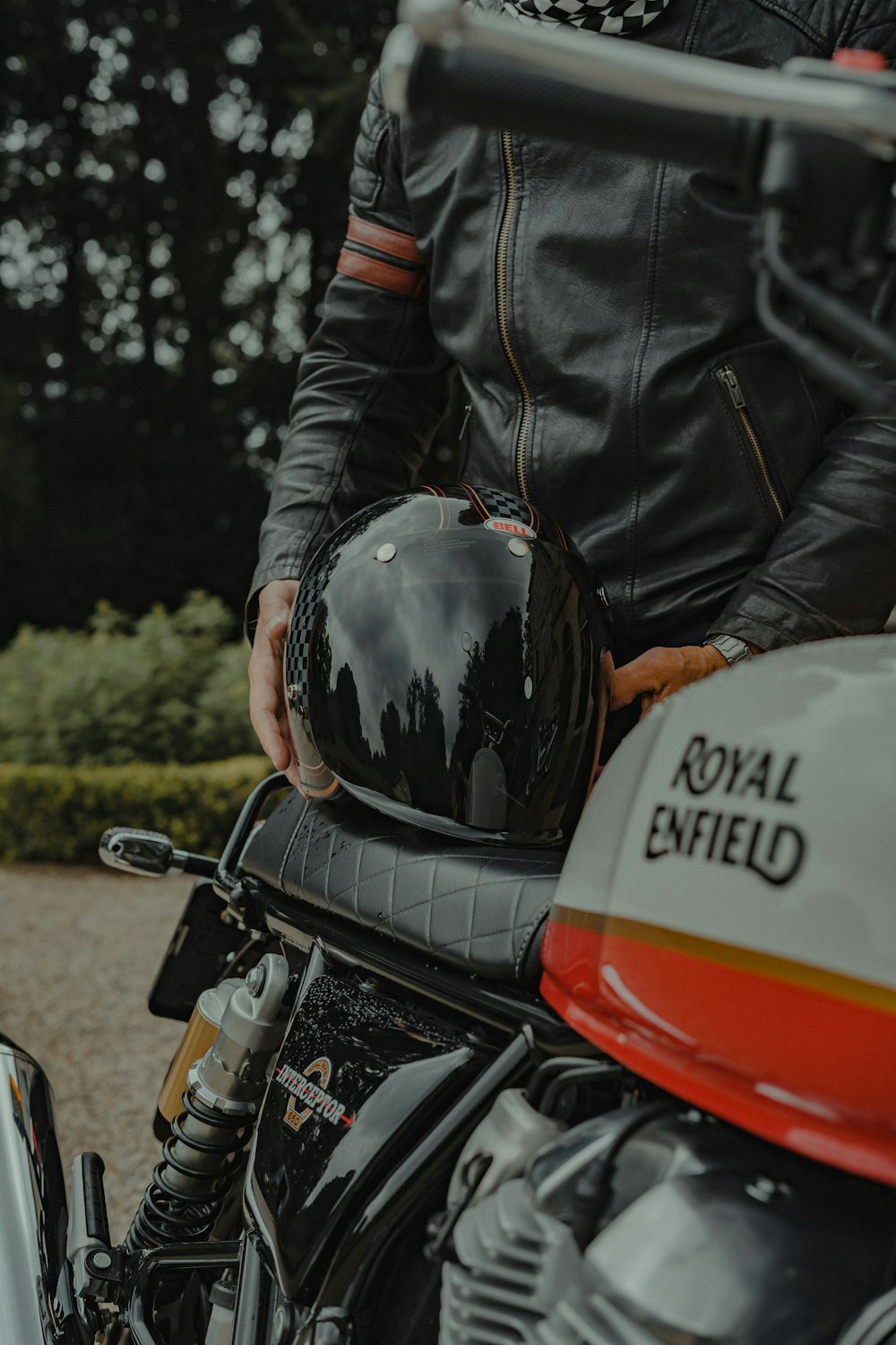 a man in a black leather jacket and helmet on a motorcycle