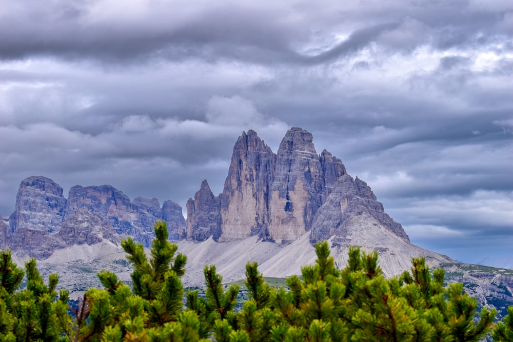 a mountain range with trees and clouds in the background