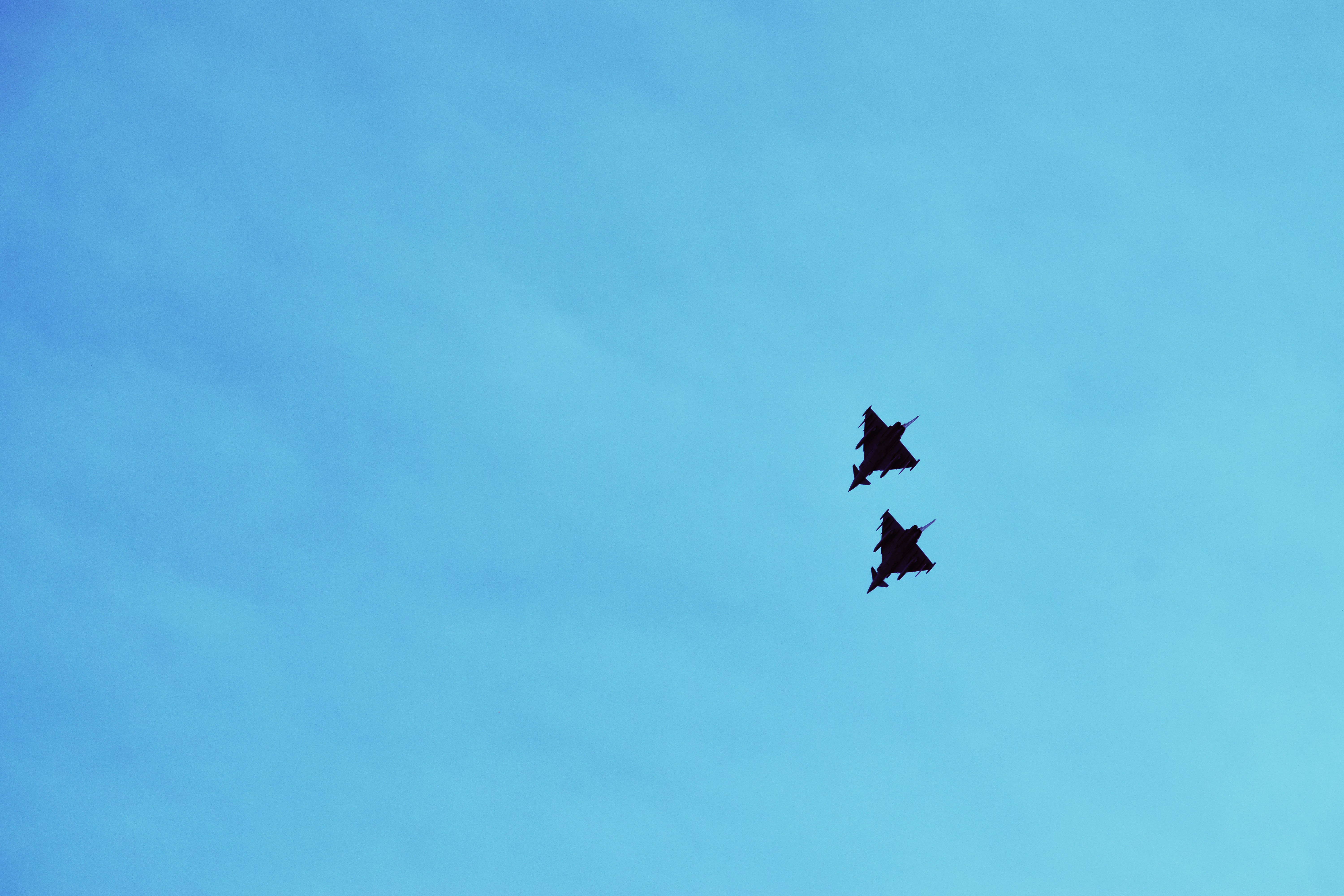 a couple of jets flying through a blue sky