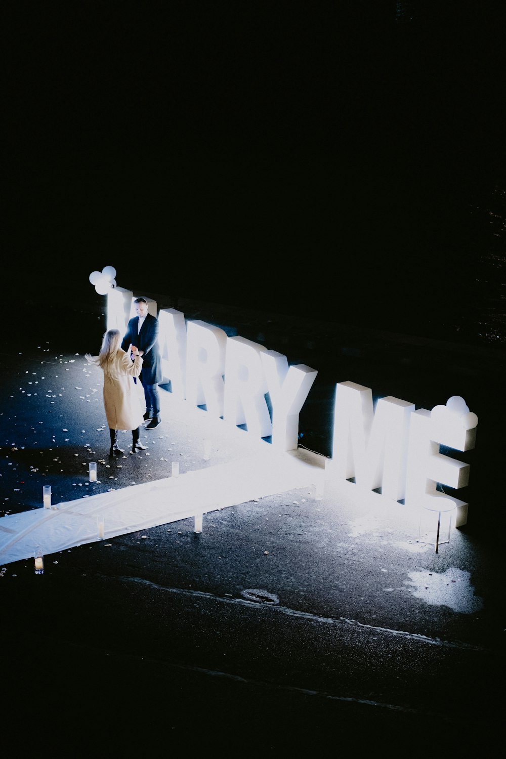 a couple of people walking down a street at night