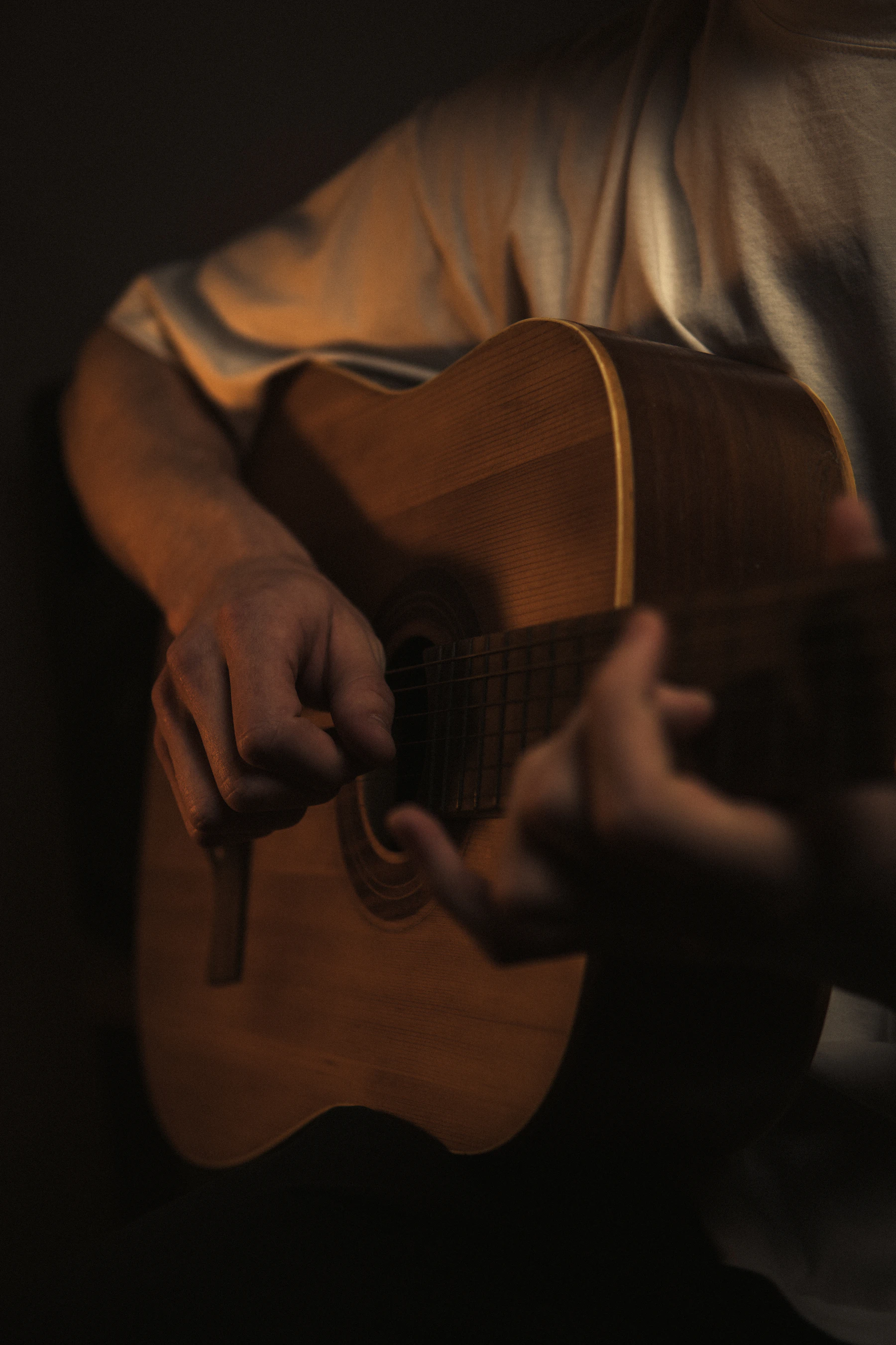 Homem tocando violão em ambiente escuro