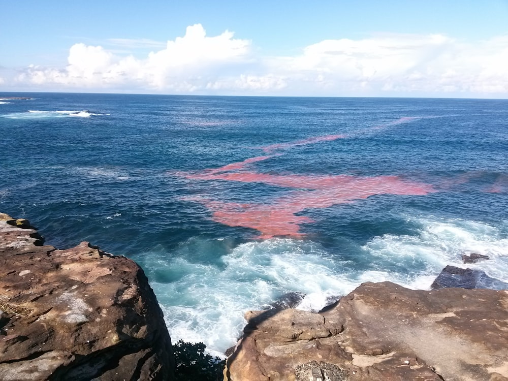 a large body of water sitting next to a rocky shore