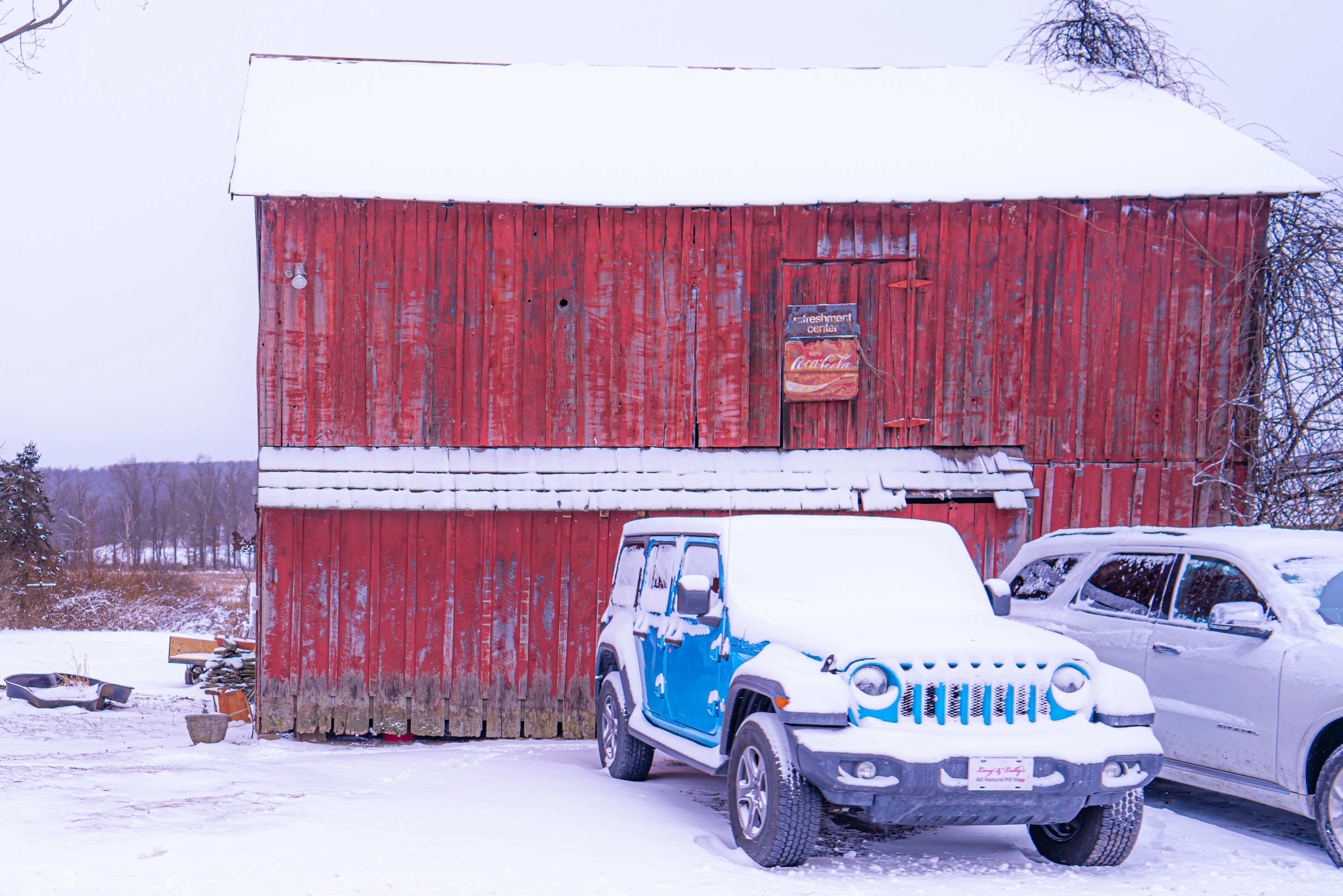 two cars parked in front of a red barn