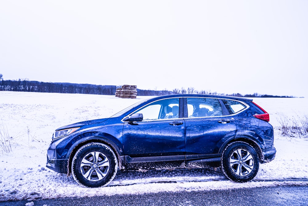 a blue car parked on a snowy road