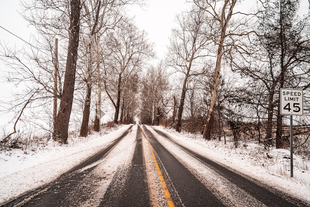 a snow covered road with a speed limit sign