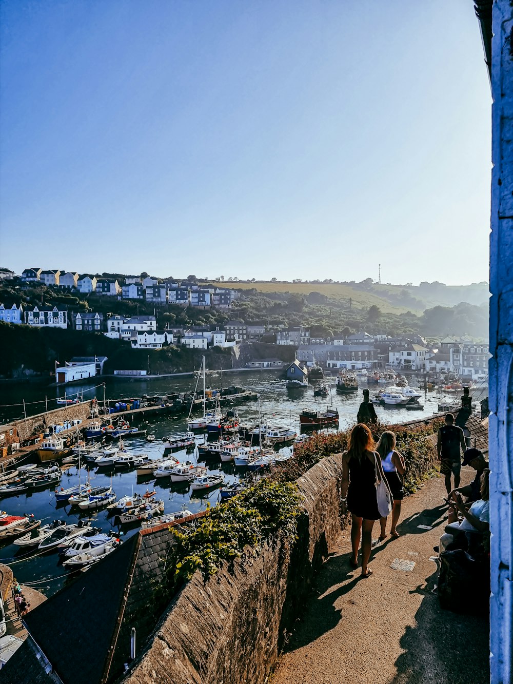 a group of people walking up a hill next to a harbor