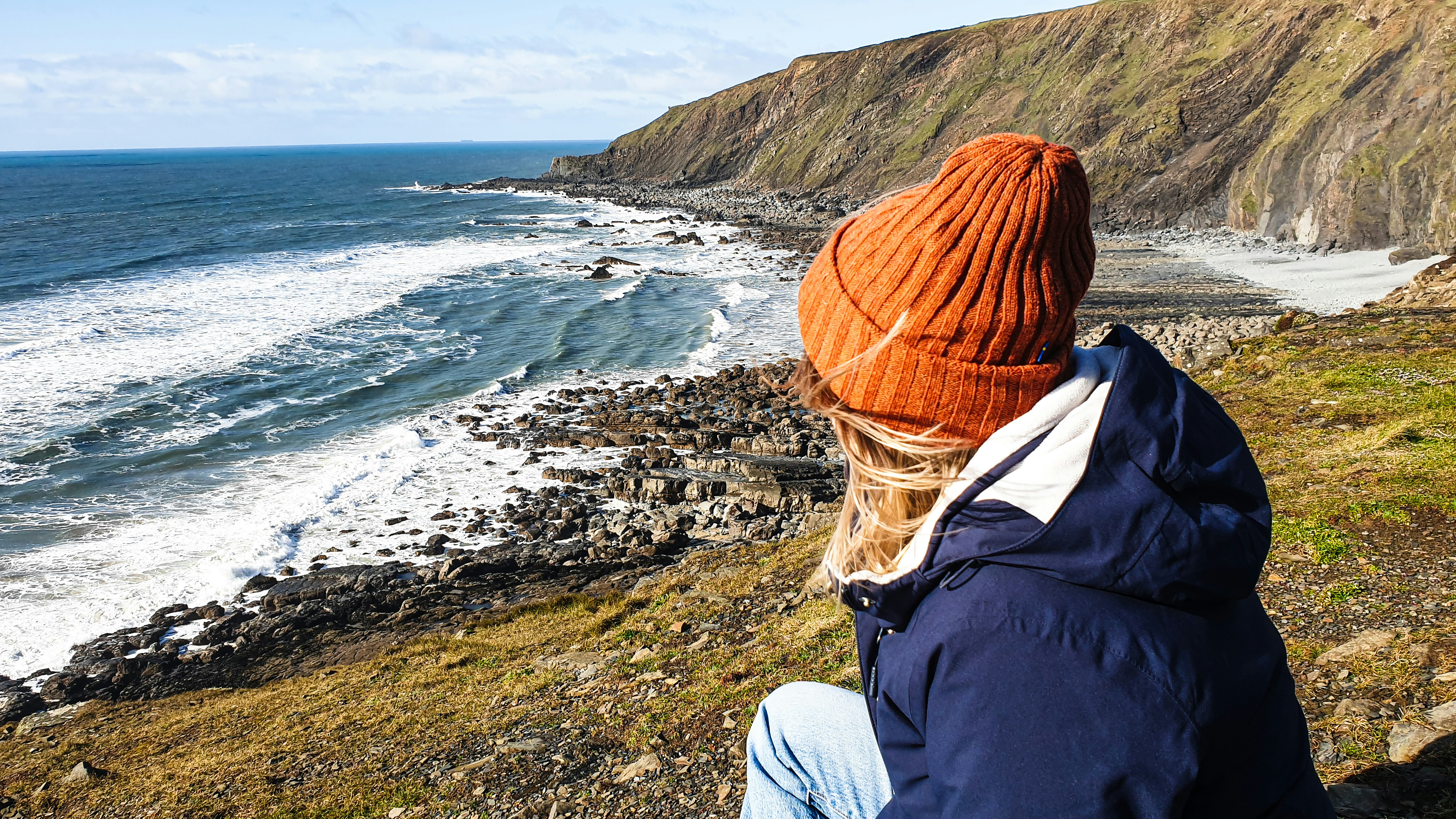 Una donna seduta su una scogliera che si affaccia sull'oceano