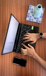 a person typing on a laptop on a wooden table