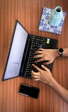 a person typing on a laptop on a wooden table