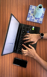 a person typing on a laptop on a wooden table