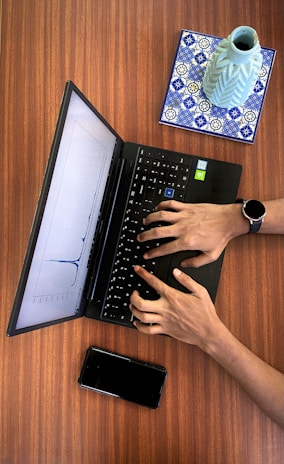 a person typing on a laptop on a wooden table