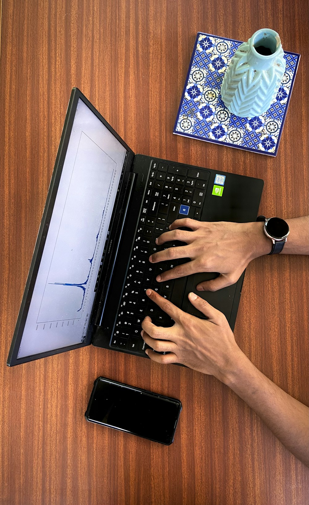 Una persona escribiendo en una computadora portátil en una mesa de madera