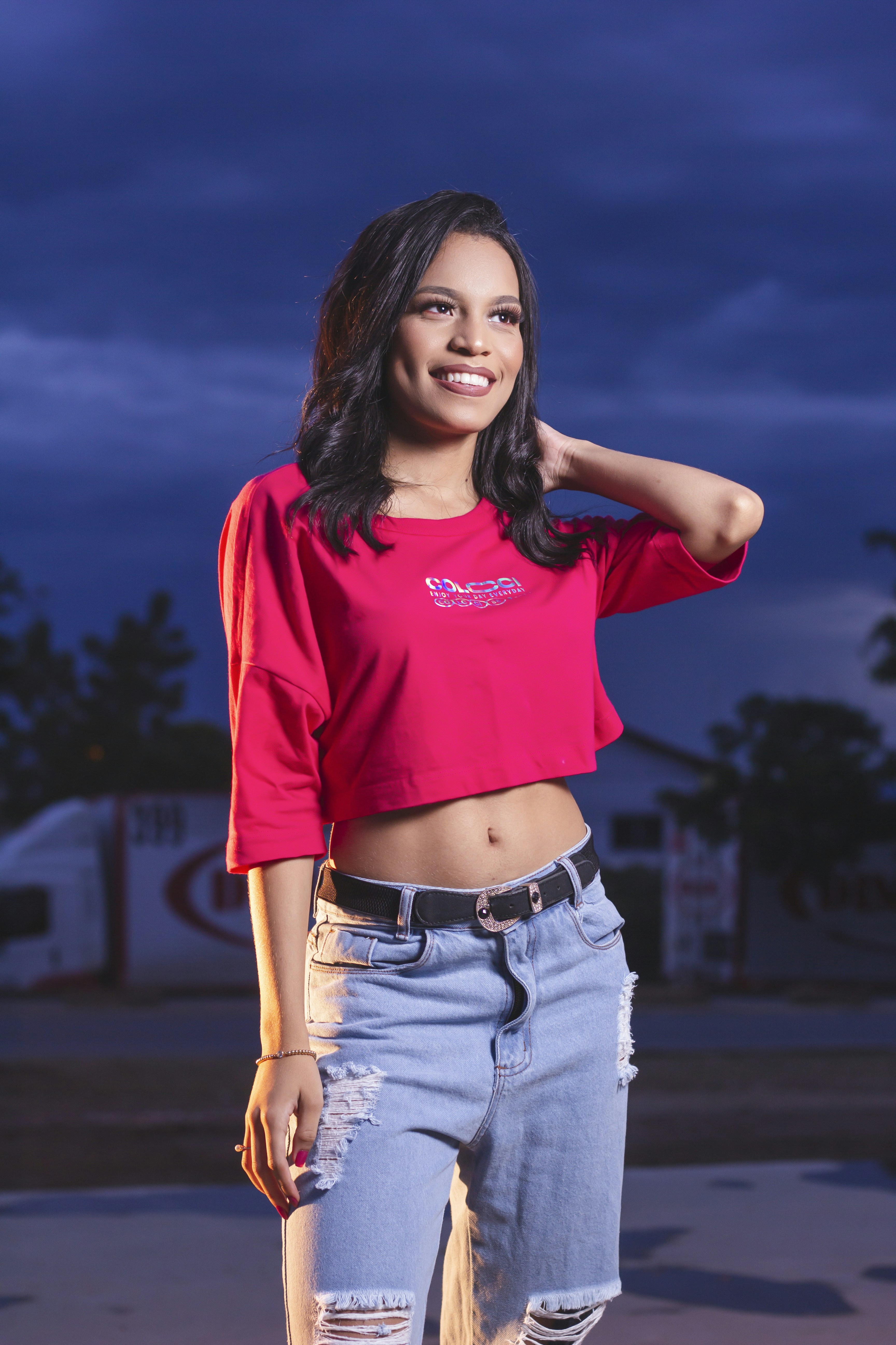 Seorang wanita mengenakan celana jeans robek dan crop top merah muda