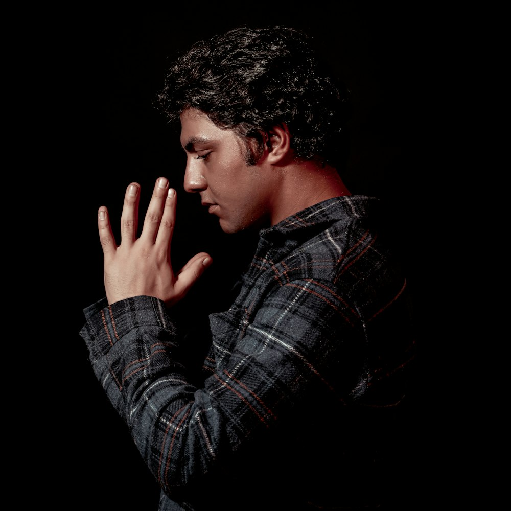 a man in a plaid shirt holding his hands together