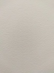 Detail of a smooth, expertly finished plaster wall in soft natural light.