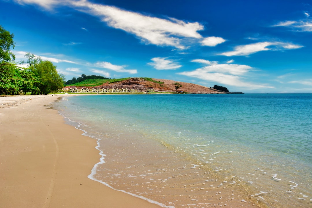 a sandy beach next to the ocean under a blue sky, Beautiful beach in Cambodia