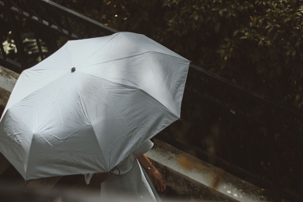 a person with a white umbrella walking down a street