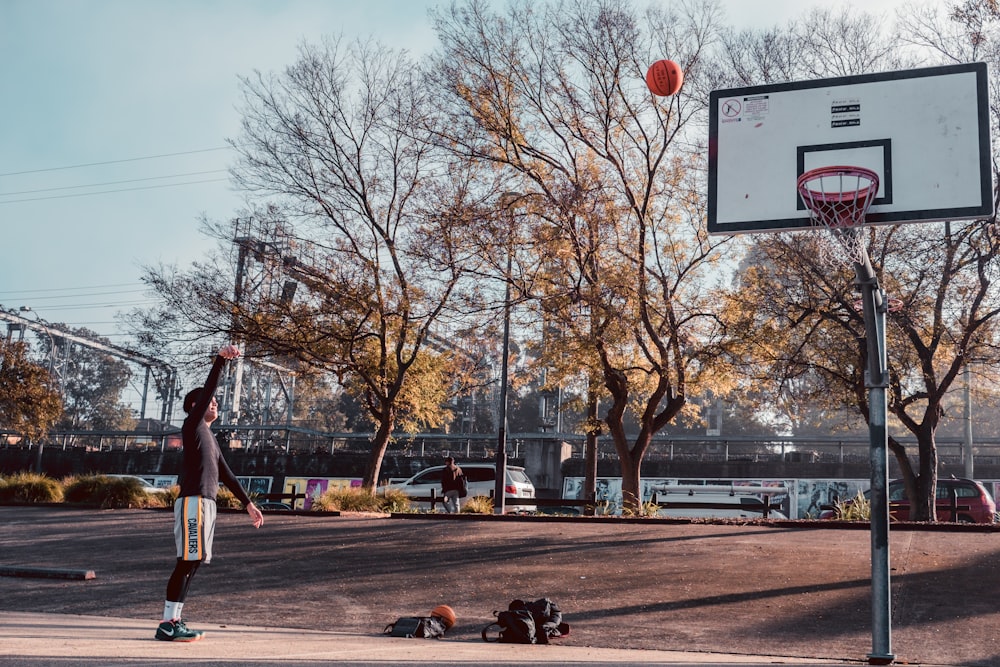 a man is playing basketball in a parking lot