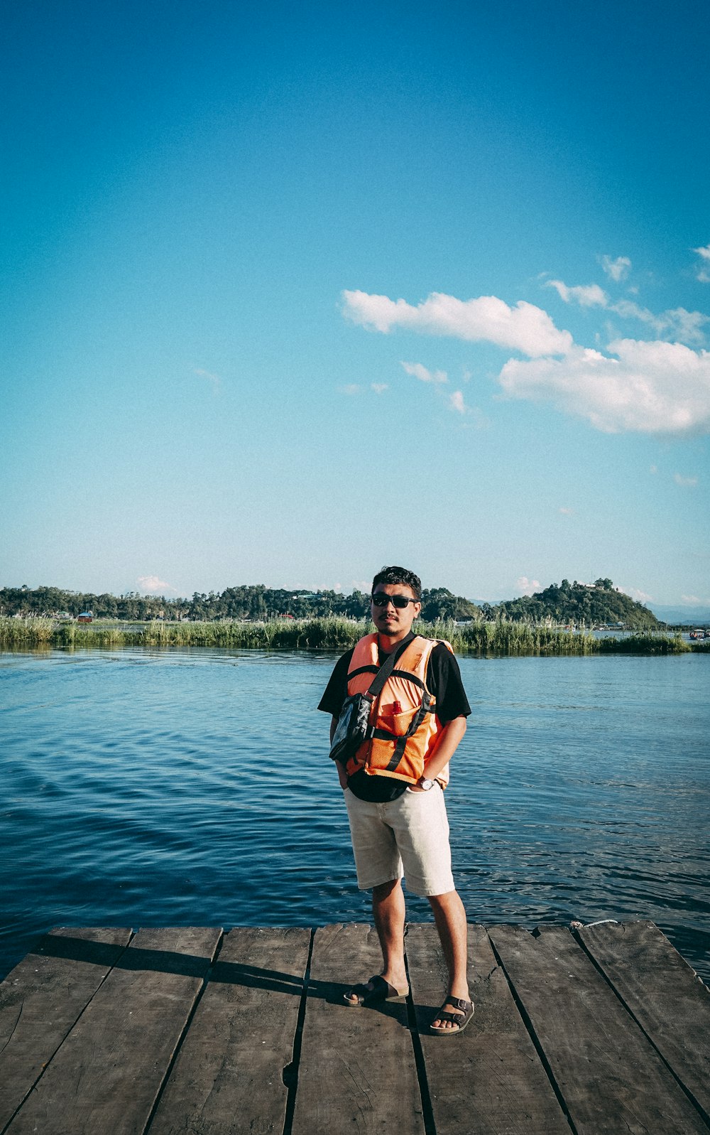 a man standing on a dock next to a body of water